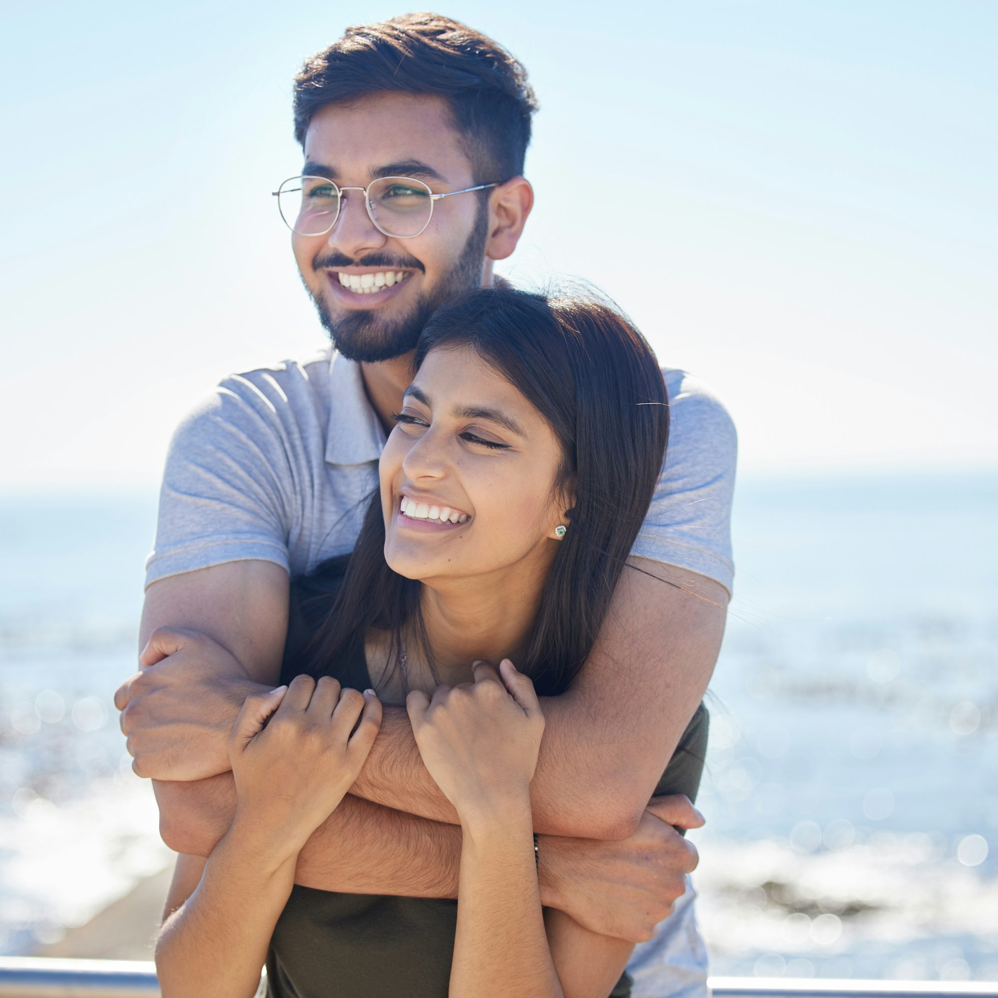 Love, ocean and happy couple hug, relax and enjoy outdoor quality time together for peace, freedom