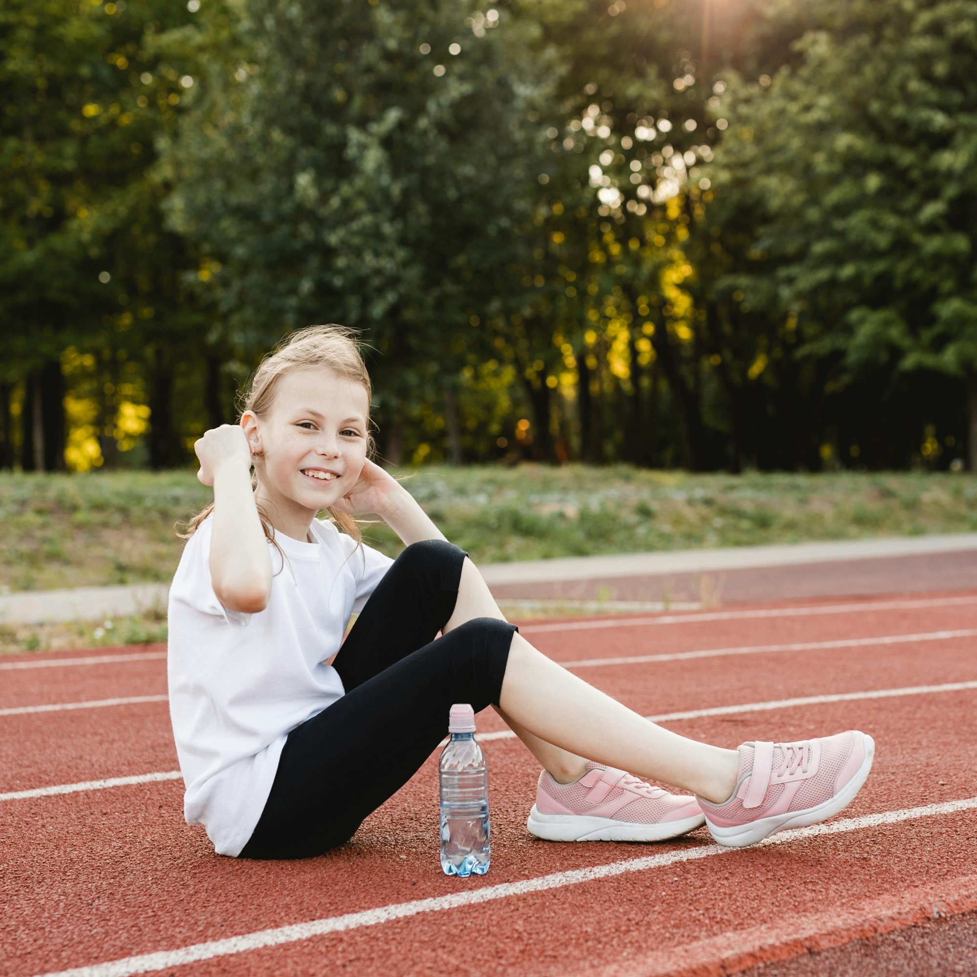 Smiling pre-teen girl taking a break after workout exercising.