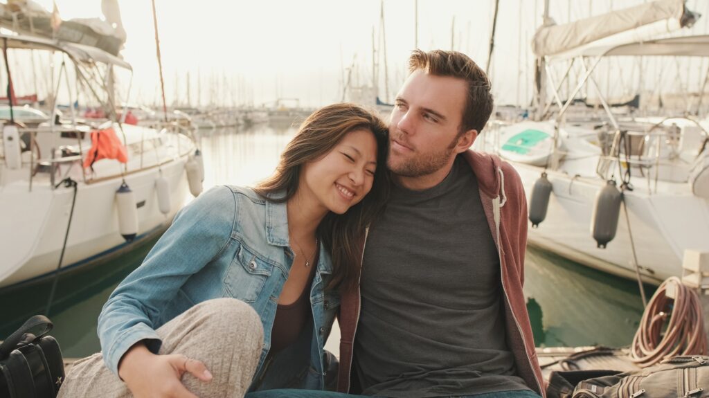 Close-up of young happy couple sitting in seaport